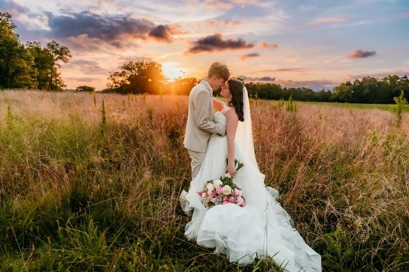 A couple standing in a field at sunset